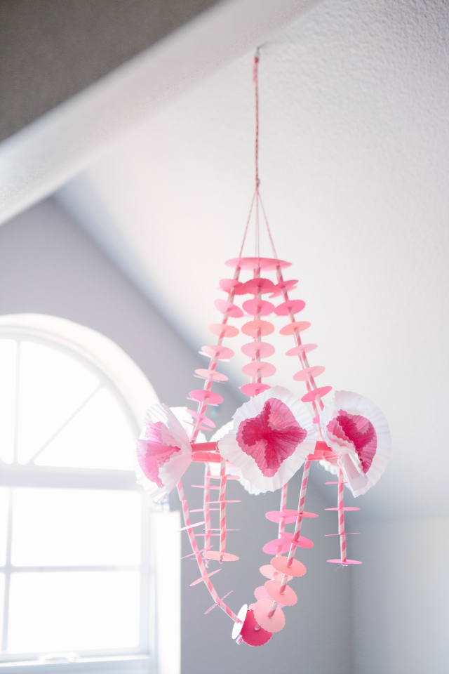 This delicate paper chandelier comes together easily with a paper punch, striped straws, and cupcake wrapper flowers! || http://designimprovised.com