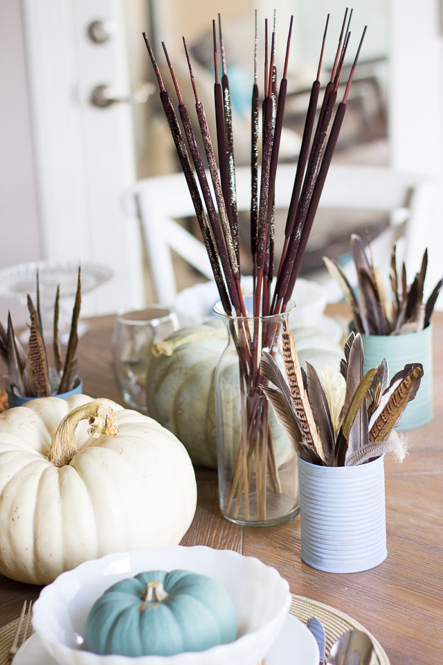 A modern Thanksgiving table with gold dipped feather arrangements and pumpkins painted in moody blues and greens || http://designimprovised.com