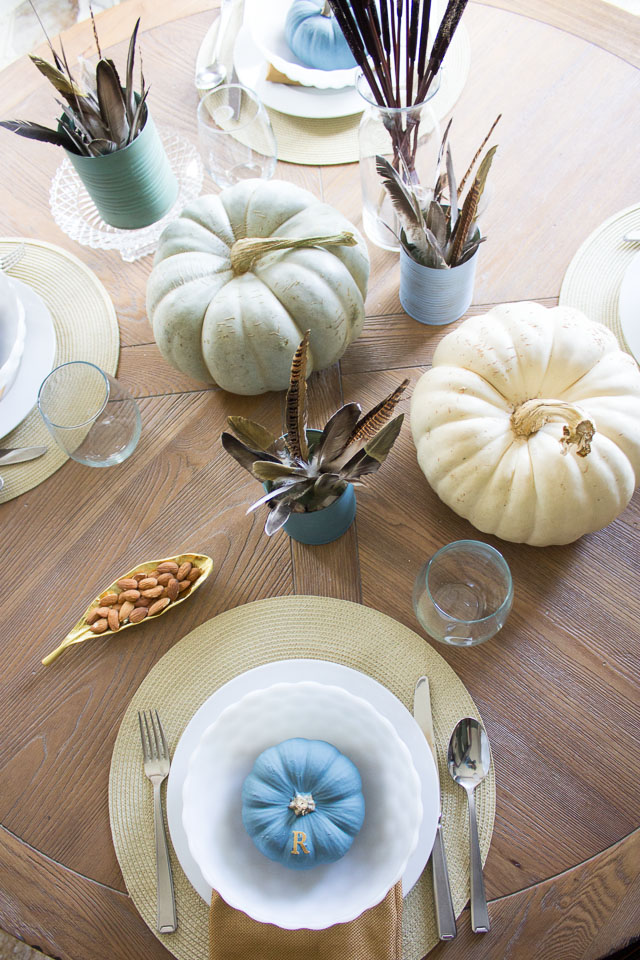 A modern Thanksgiving table with gold dipped feather arrangements and pumpkins painted in moody blues and greens || http://designimprovised.com