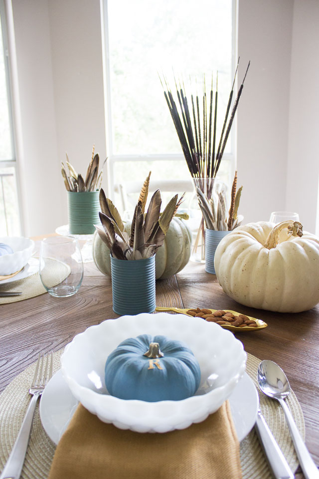 A modern Thanksgiving table with gold dipped feather arrangements and pumpkins painted in moody blues and greens || http://designimprovised.com