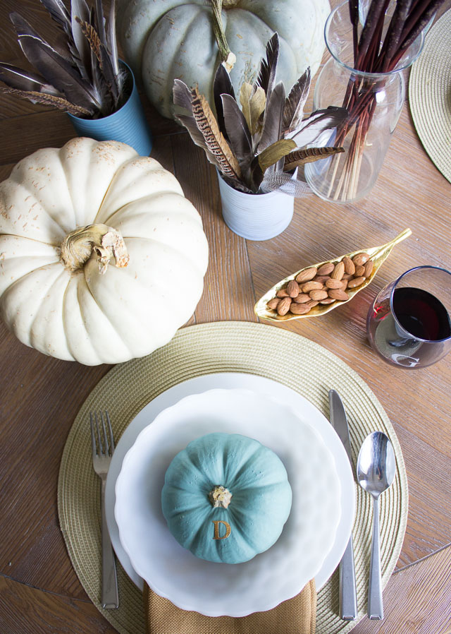 A modern Thanksgiving table with gold dipped feather arrangements and pumpkins painted in moody blues and greens || http://designimprovised.com