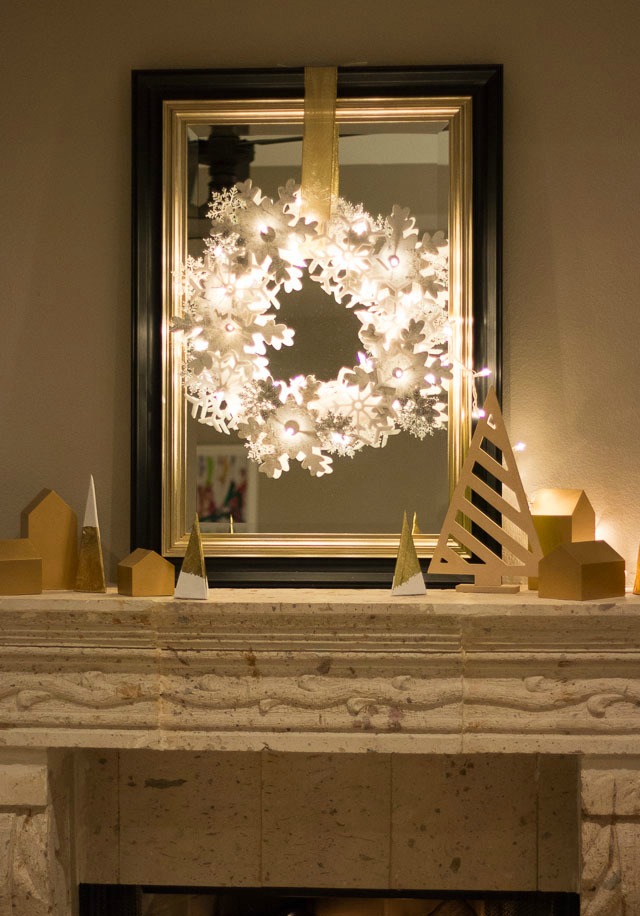 Glowing snowflake wreath over fireplace mantel