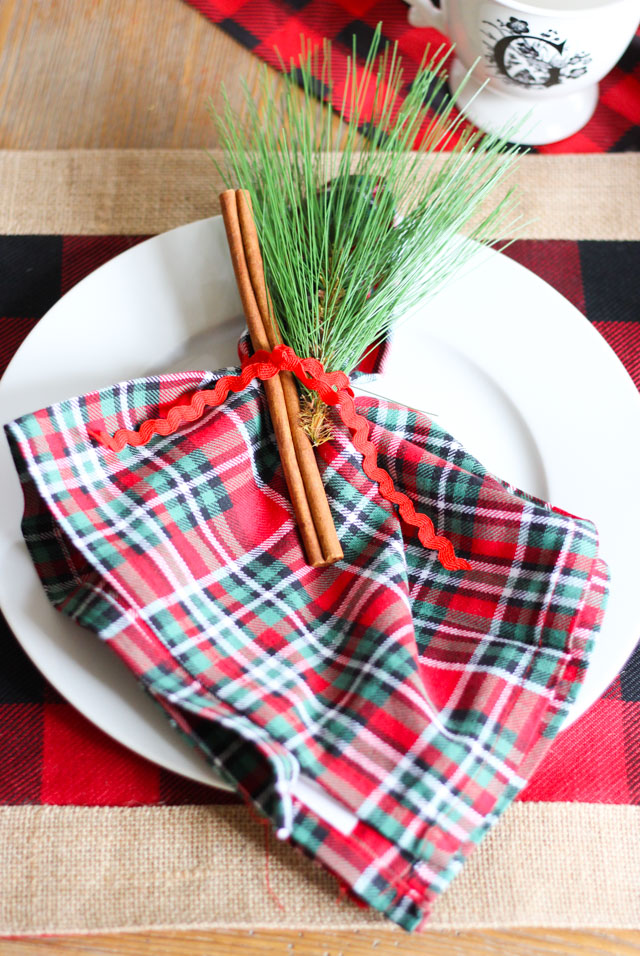 Simple and sweet Christmas place setting idea - tie a cinnamon stick and evergreen sprig around a napkin!