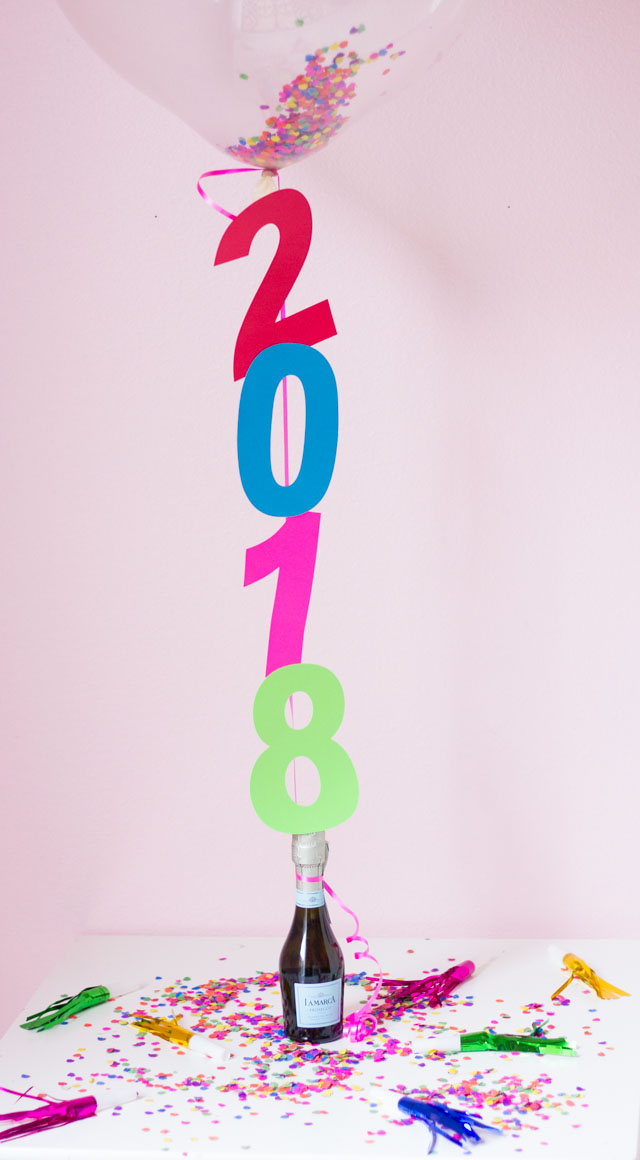 The perfect DIYt New Years Eve decoration - confetti filled number balloons with a champagne balloon weight!