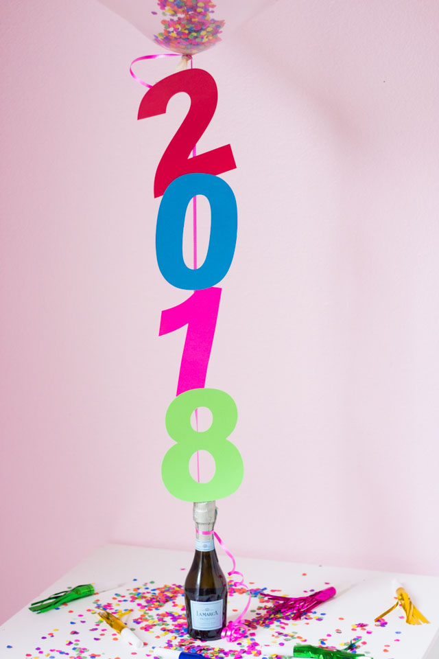 The perfect DIYt New Years Eve decoration - confetti filled number balloons with a champagne balloon weight!