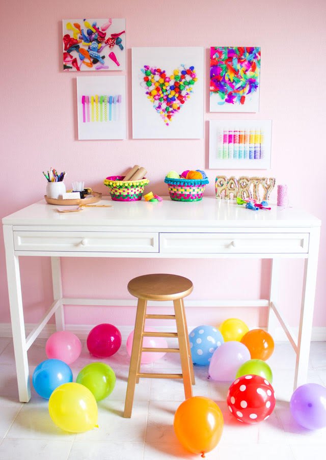 Pink craft room with colorful craft supply wall art and balloons