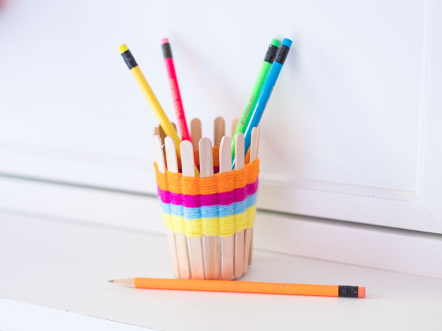 Use popsicle sticks and yarn to make these pretty woven pencil cups. Such a fun kids craft! #yarncrafts #kidscrafts #popsiclestickcrafts #popsiclestickweaving #kidsweaving