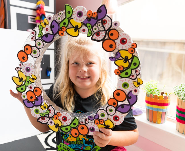 Child holding Halloween eyeball wreath