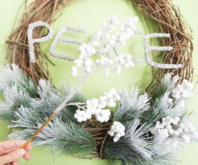 Adding white Christmas greenery to grapevine wreath